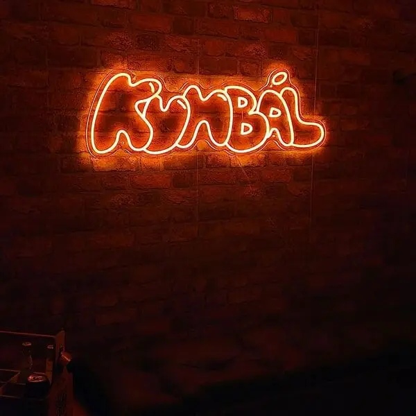 Oranžový neónový nápis Kumbál na tehlovej stene — realizácia Neonworld